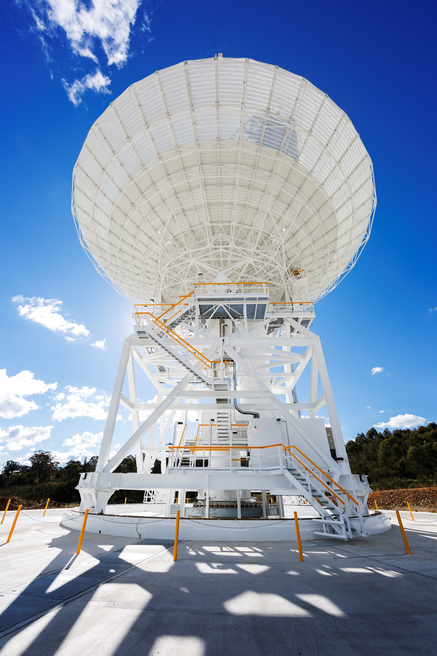 A white antenna stretches across the photo, backlit by the Sun on a bright blue sky.