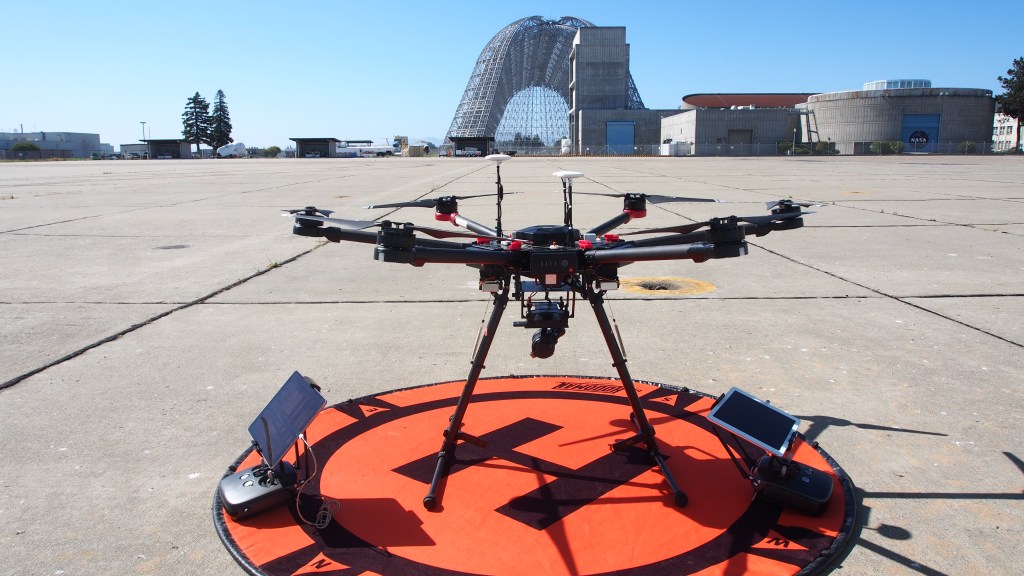 eight arm large drone on ground with historic unskinned hangar one in background at Ames Research Center