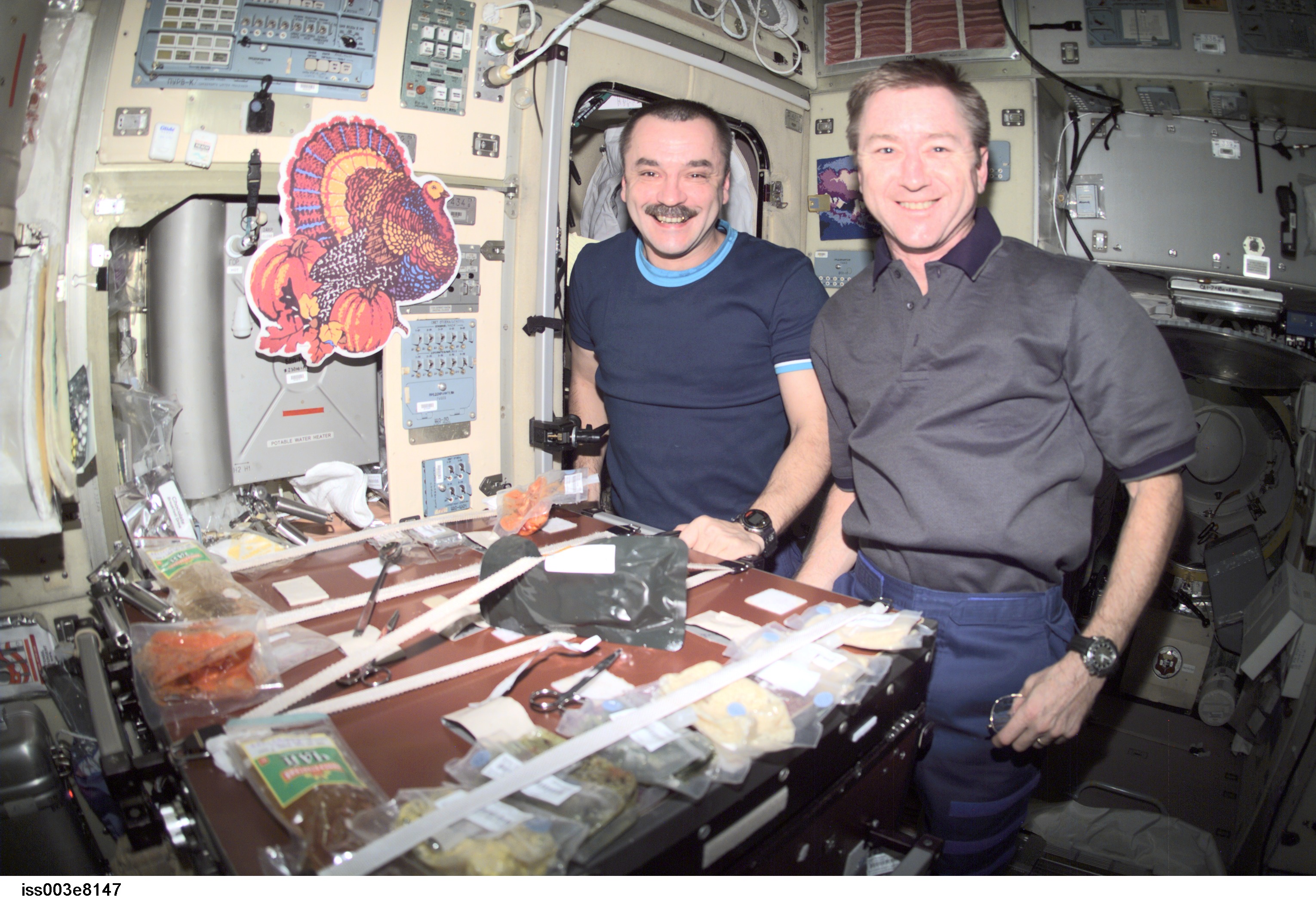 Cosmonaut Mikhail Tyurin (left), Expedition 3 flight engineer, and astronaut Frank L. Culbertson, mission commander, eat a Thanksgiving meal in the...